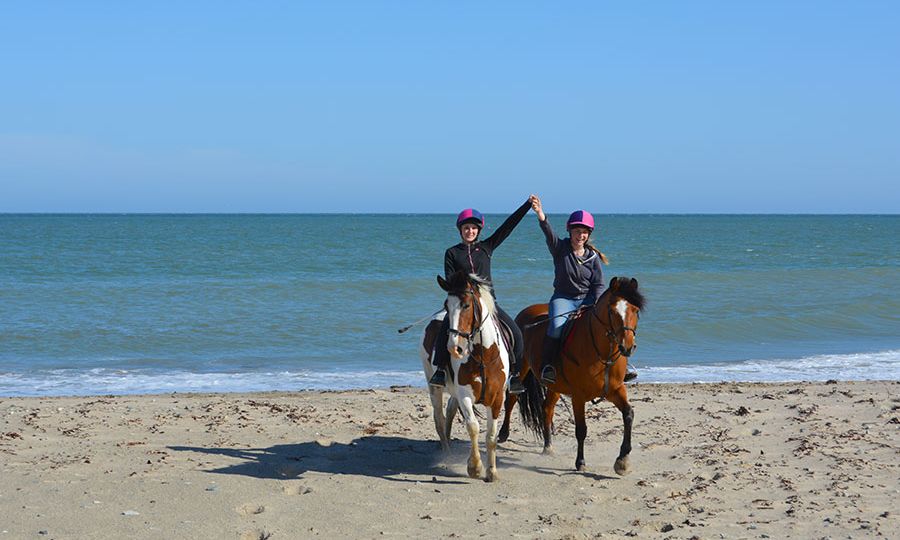 happy girls on horses on the beach