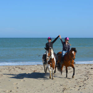 happy girls on horses on the beach